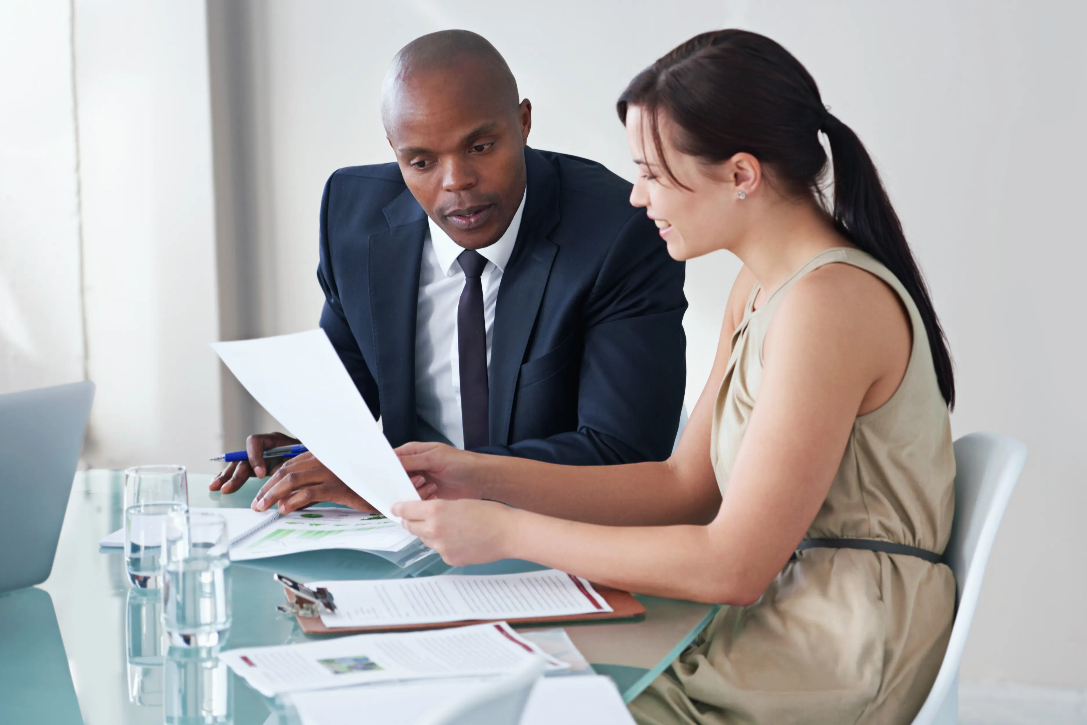 Business people in an office meeting with documentation, where a diverse group of employees discuss a finance report, company paperwork, and financial projections or strategy planning, collaborating as staff.