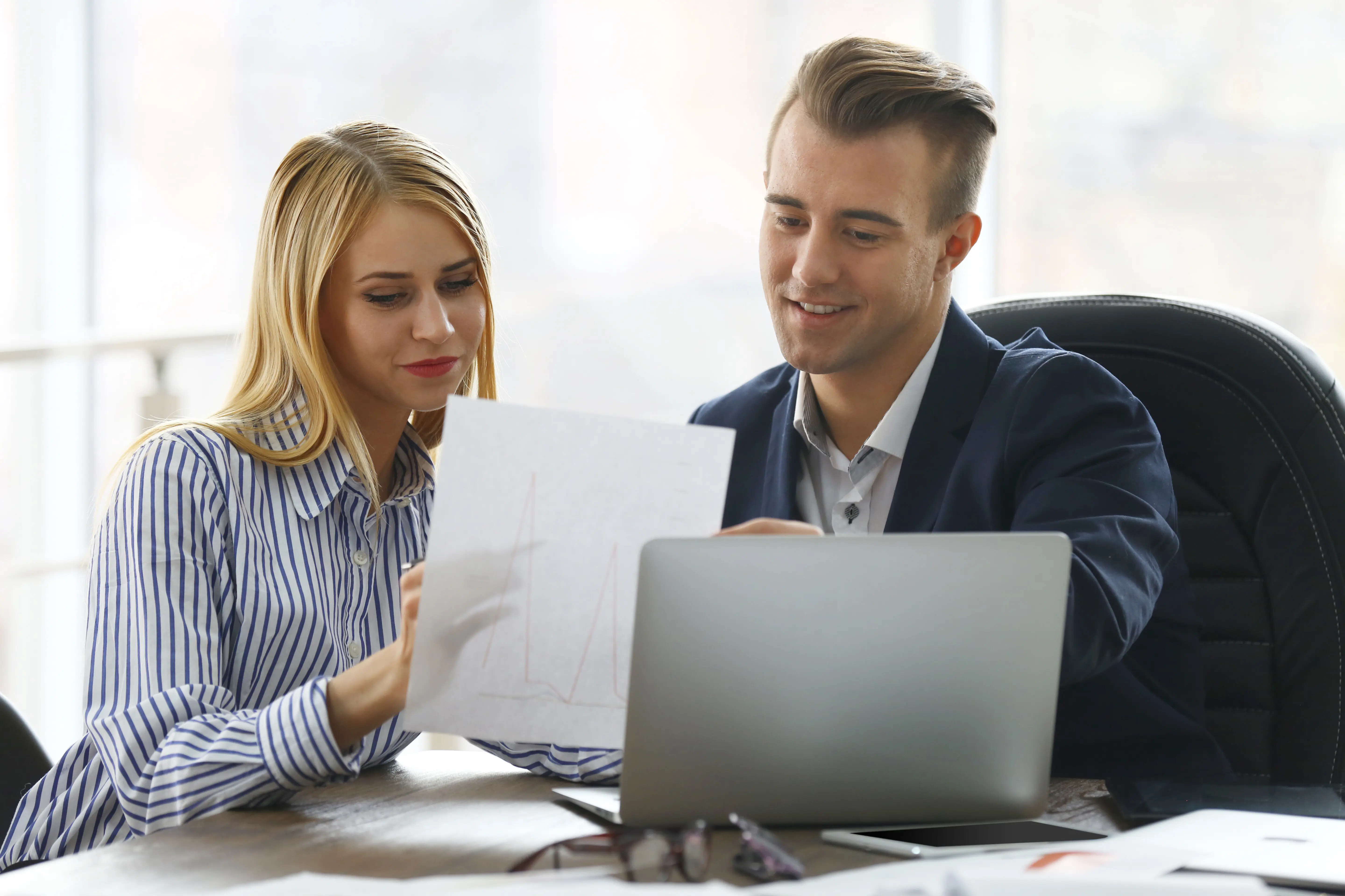 A businessman and a businesswoman working in an office.
