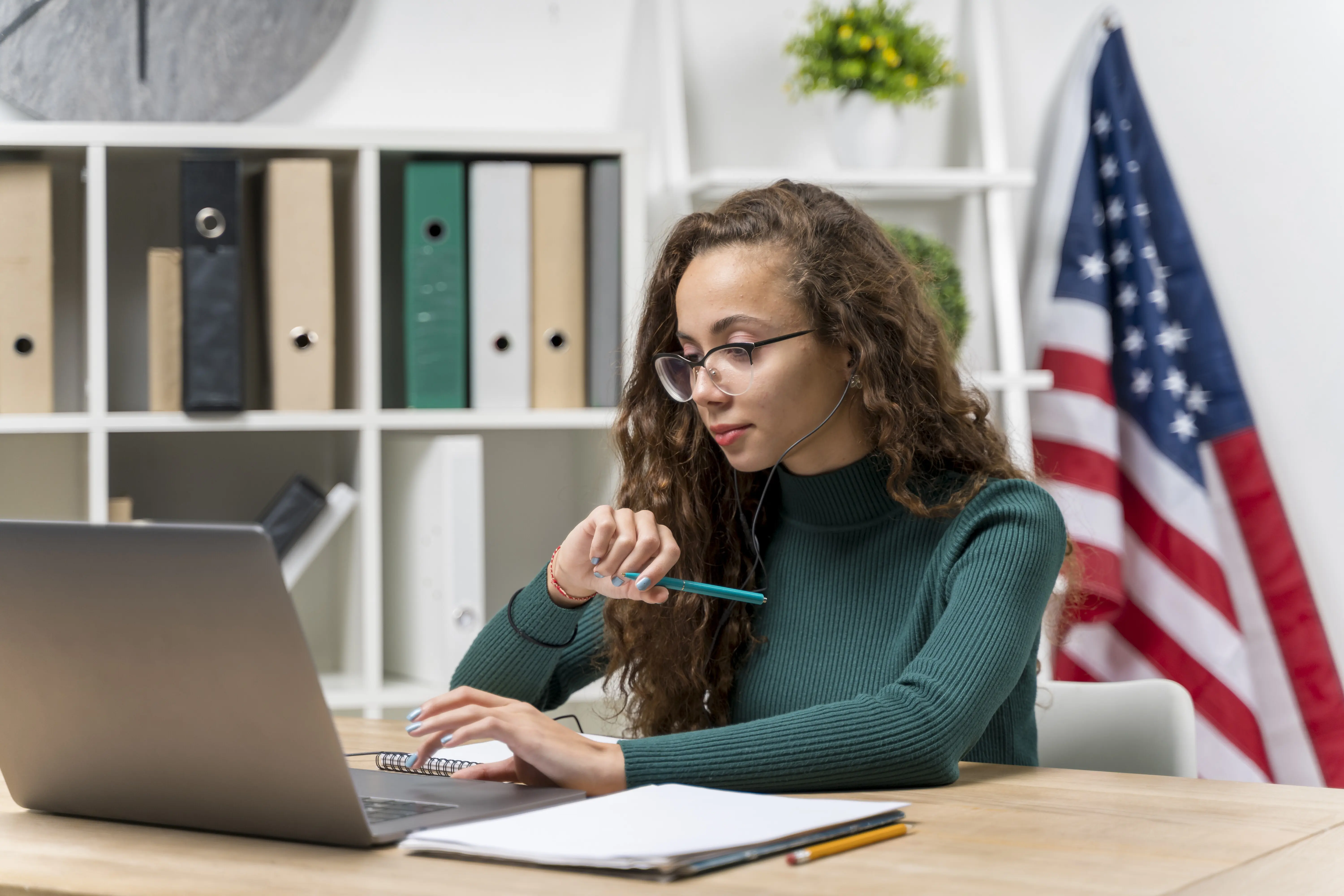 Medium shot of a girl studying with a laptop and headphones.